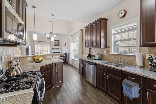 kitchen featuring dark brown cabinetry, a sink, appliances with stainless steel finishes, light stone countertops, and dark wood-style floors