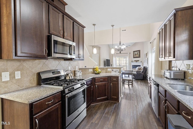 kitchen with dark wood finished floors, decorative backsplash, appliances with stainless steel finishes, a sink, and dark brown cabinets