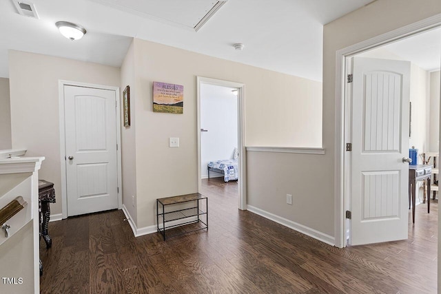 corridor featuring dark wood-type flooring, visible vents, and baseboards