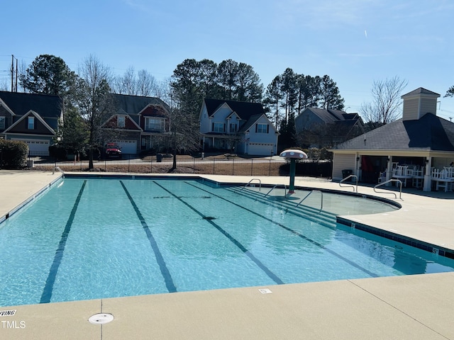 community pool featuring a residential view, fence, and a patio