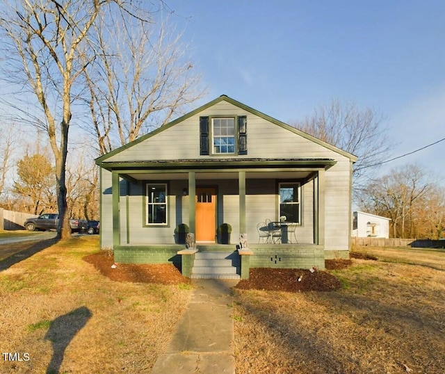 bungalow-style home featuring a front yard and covered porch