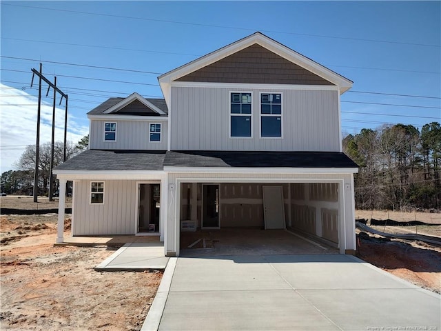 view of front of house with an attached garage, concrete driveway, and roof with shingles