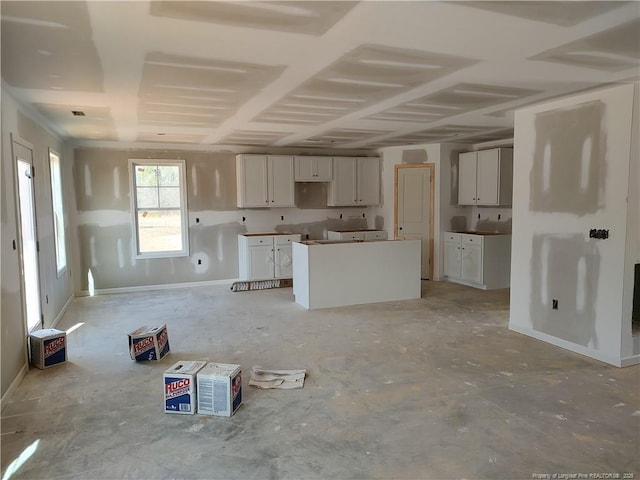 kitchen featuring baseboards, white cabinets, and a center island