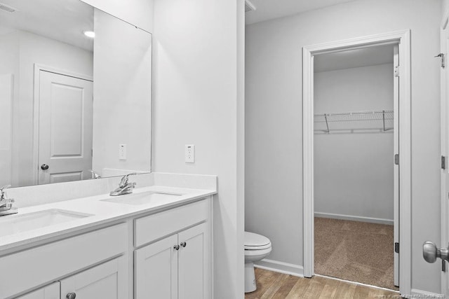 821 Tori Dr, Spring Lake, NC 28390 - bathroom featuring double vanity, toilet, a spacious closet, wood finished floors, and baseboards