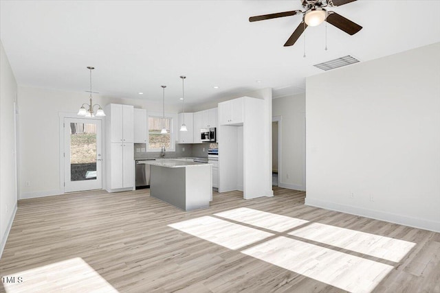 kitchen with white cabinetry, a center island, pendant lighting, stainless steel appliances, and light hardwood / wood-style floors