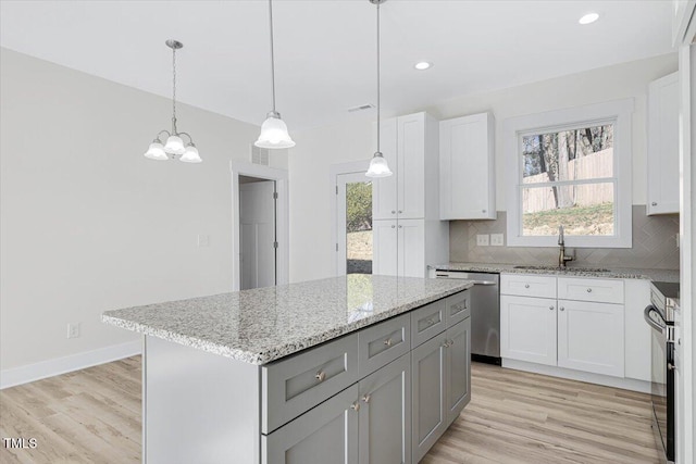 kitchen with sink, a center island, hanging light fixtures, stainless steel dishwasher, and white cabinets