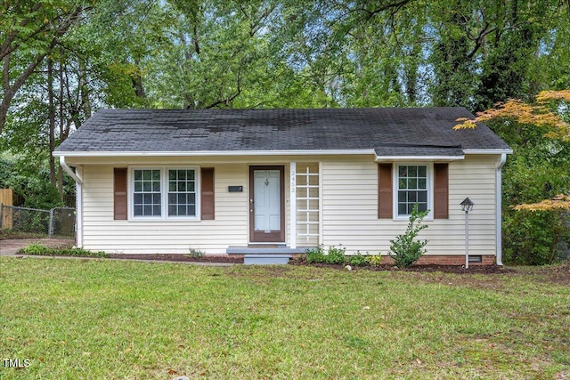 ranch-style house with a shingled roof, fence, and a front lawn