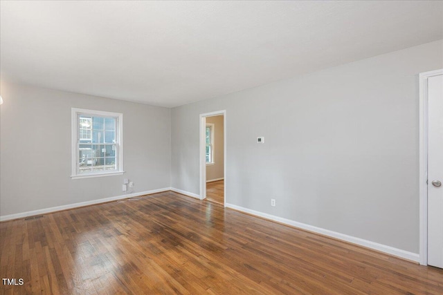 spare room featuring wood-type flooring and baseboards