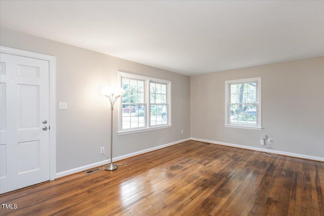 spare room featuring baseboards, plenty of natural light, visible vents, and hardwood / wood-style floors