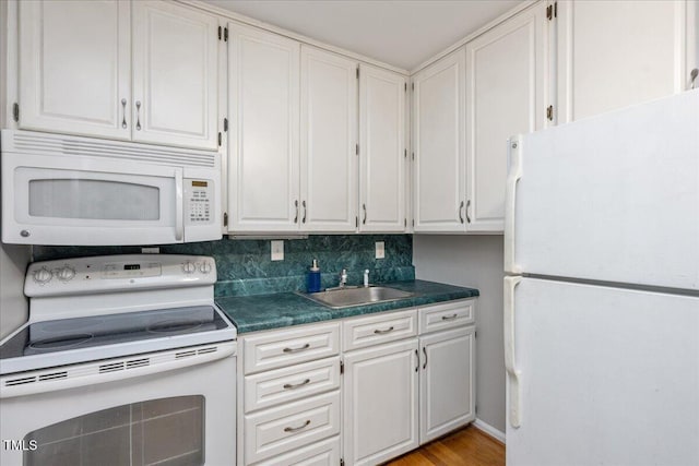 kitchen with white appliances, a sink, white cabinets, decorative backsplash, and dark countertops