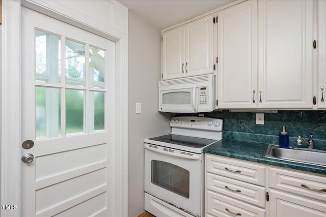 kitchen featuring white appliances, a sink, white cabinets, backsplash, and dark countertops