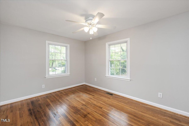 unfurnished room with hardwood / wood-style flooring, ceiling fan, visible vents, and baseboards