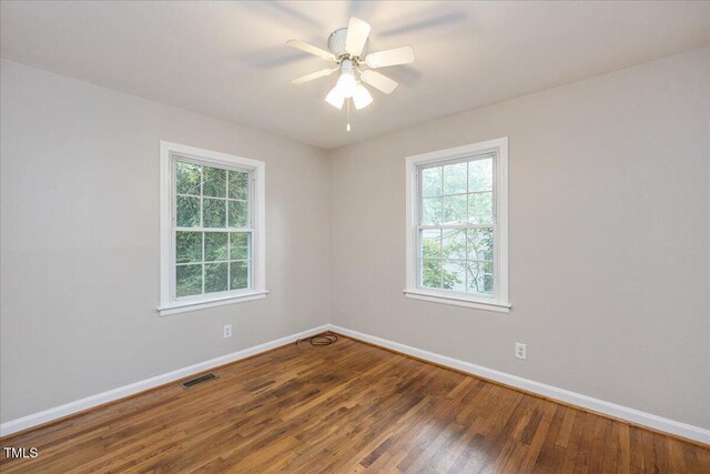 spare room featuring wood finished floors, visible vents, and baseboards