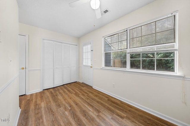 unfurnished bedroom with hardwood / wood-style flooring, ceiling fan, and a closet