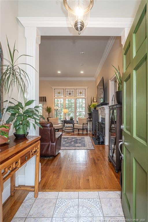 entryway featuring decorative columns, crown molding, and light tile patterned floors