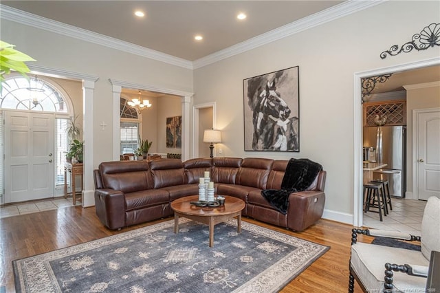 living room with an inviting chandelier, crown molding, and light hardwood / wood-style floors