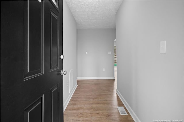 corridor featuring light hardwood / wood-style flooring and a textured ceiling