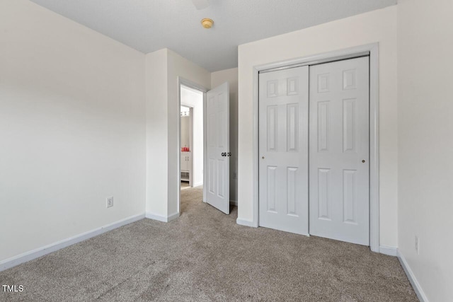 unfurnished bedroom with light carpet, baseboards, and a closet