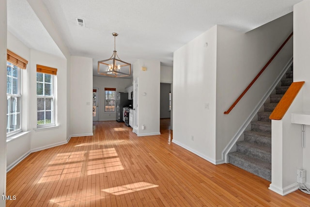 interior space featuring baseboards, light wood finished floors, stairway, and an inviting chandelier