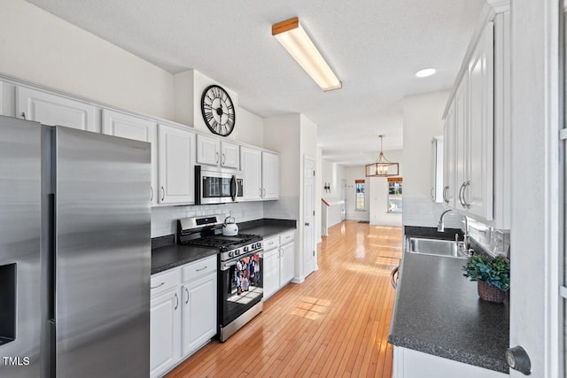 kitchen featuring dark countertops, appliances with stainless steel finishes, white cabinets, and a sink