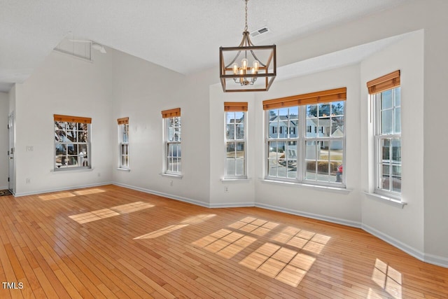 entrance foyer featuring light wood-style floors, a chandelier, vaulted ceiling, and baseboards