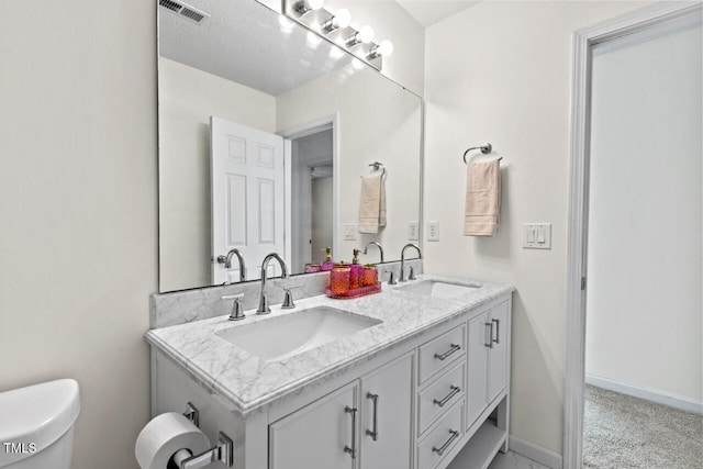 bathroom featuring double vanity, baseboards, visible vents, and a sink