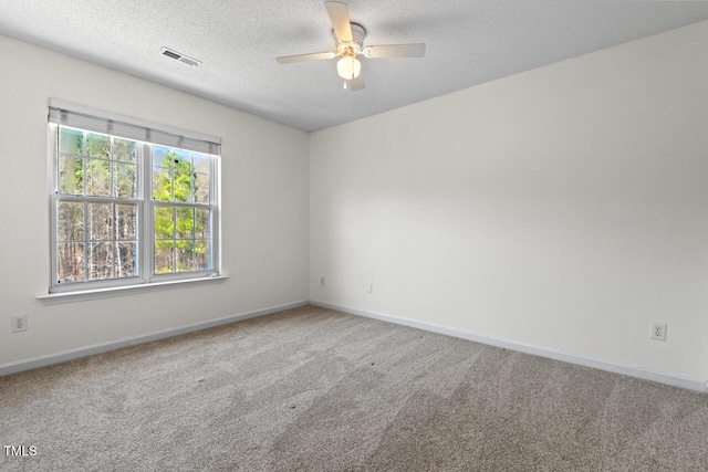 empty room with carpet, visible vents, a textured ceiling, and baseboards