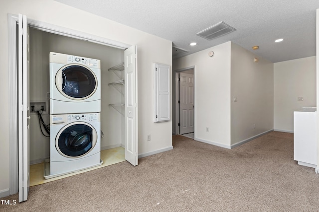 clothes washing area with light carpet, stacked washer and dryer, laundry area, visible vents, and a textured ceiling