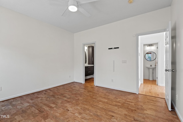 unfurnished bedroom with a sink, wood finished floors, and baseboards