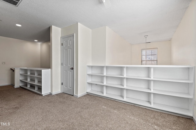 interior space with a textured ceiling, carpet flooring, visible vents, and baseboards