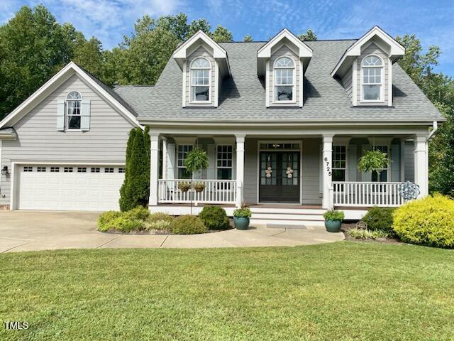 cape cod home featuring french doors, a garage, covered porch, and a front yard