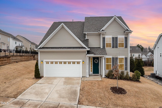 traditional-style home with a shingled roof, driveway, an attached garage, and fence