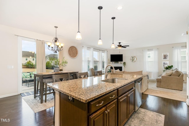 kitchen featuring ceiling fan with notable chandelier, dark wood-type flooring, a sink, dark brown cabinets, and stainless steel dishwasher