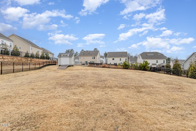 view of yard featuring an outbuilding, a storage unit, a fenced backyard, and a residential view