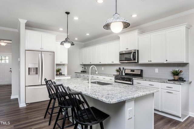 kitchen with decorative light fixtures, white cabinetry, an island with sink, sink, and stainless steel appliances