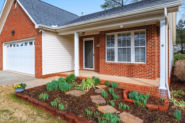 doorway to property featuring concrete driveway, brick siding, an attached garage, and a shingled roof