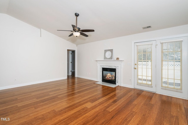 unfurnished living room with visible vents, vaulted ceiling, a fireplace, and wood finished floors