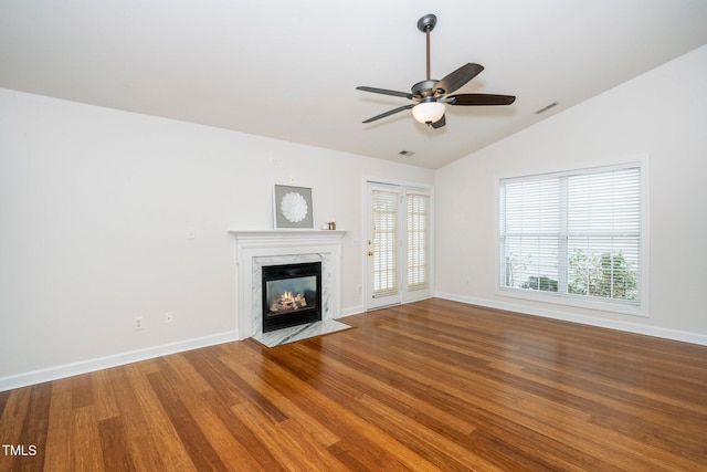 unfurnished living room featuring visible vents, vaulted ceiling, wood finished floors, and a high end fireplace