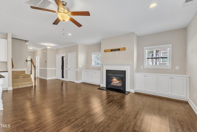 unfurnished living room with a glass covered fireplace, visible vents, stairway, and wood finished floors