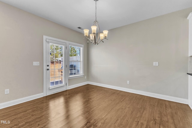 empty room with an inviting chandelier, visible vents, baseboards, and wood finished floors