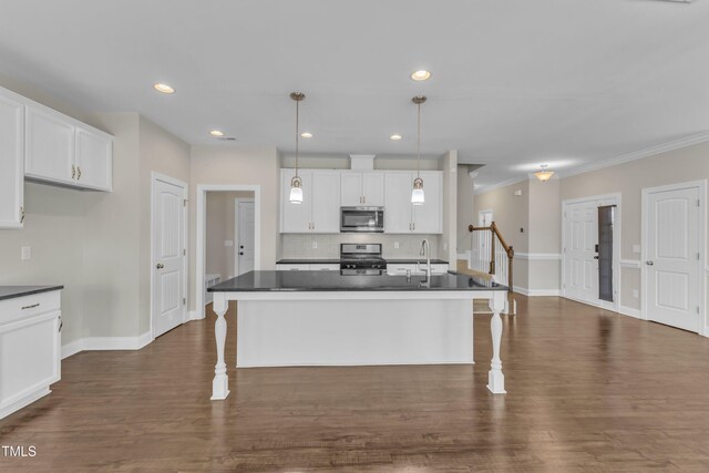 kitchen with stainless steel appliances, a breakfast bar area, dark countertops, and white cabinetry