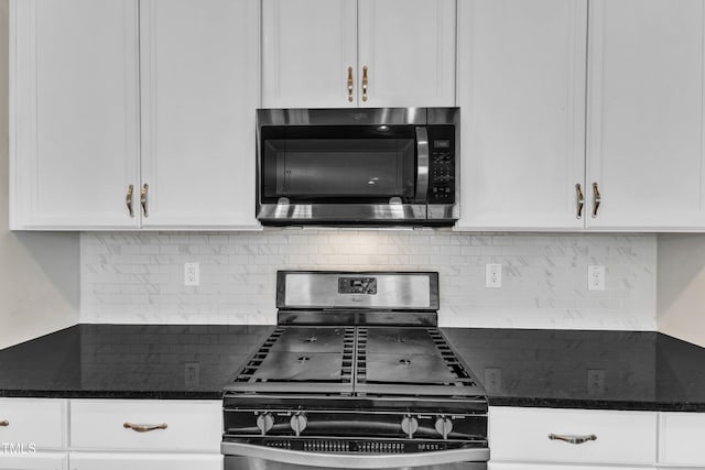 kitchen featuring white cabinets, tasteful backsplash, dark stone counters, and stainless steel appliances