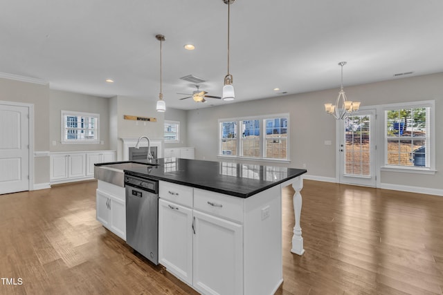 kitchen with wood finished floors, a sink, visible vents, stainless steel dishwasher, and dark countertops