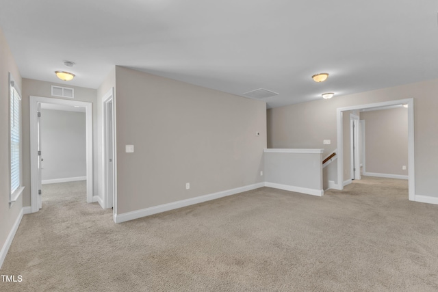 spare room featuring visible vents, light carpet, and baseboards