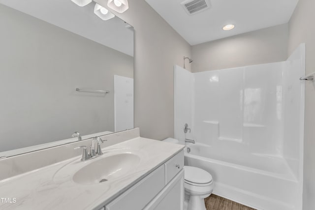 full bath with visible vents, toilet, washtub / shower combination, vanity, and wood finished floors