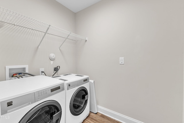 washroom featuring baseboards, laundry area, light wood-style flooring, and washer and dryer