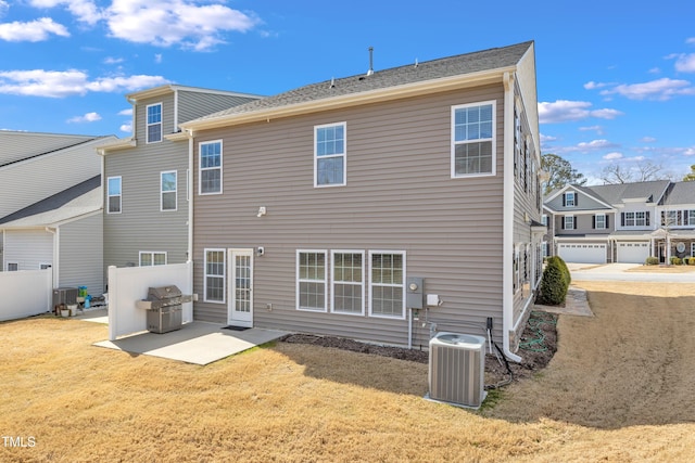 rear view of house with central air condition unit, a patio area, fence, and a yard