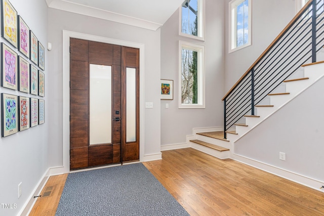 entryway with a towering ceiling and light wood-type flooring