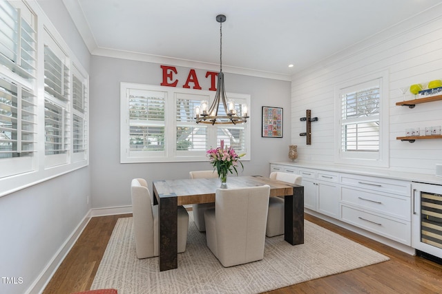 dining space featuring hardwood / wood-style flooring, a notable chandelier, a wealth of natural light, and wine cooler