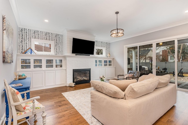 living room featuring a brick fireplace, wood-type flooring, and ornamental molding